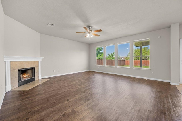 215 Gainer Dr, Hutto, TX 78634 - unfurnished living room with ceiling fan, wood finished floors, baseboards, and a tiled fireplace