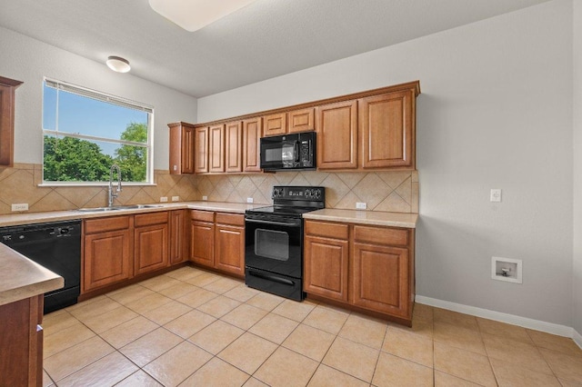 215 Gainer Dr, Hutto, TX 78634 - kitchen featuring black appliances, a sink, brown cabinetry, and decorative backsplash