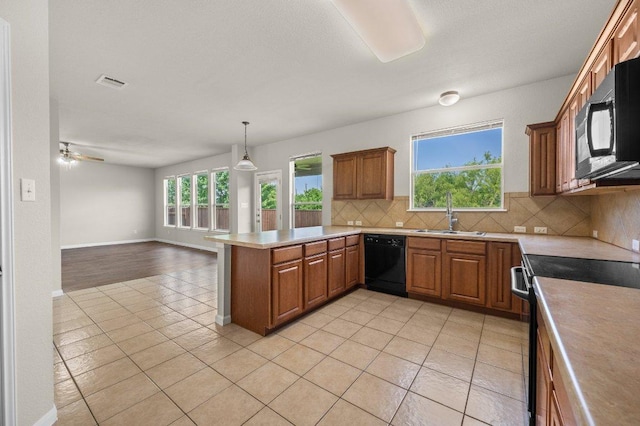 215 Gainer Dr, Hutto, TX 78634 - kitchen with black appliances, a sink, decorative backsplash, light tile patterned floors, and a peninsula