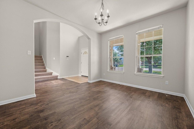 215 Gainer Dr, Hutto, TX 78634 - unfurnished room with arched walkways, wood finished floors, a chandelier, baseboards, and stairway