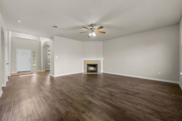 215 Gainer Dr, Hutto, TX 78634 - unfurnished living room featuring ceiling fan, arched walkways, dark wood-type flooring, and baseboards