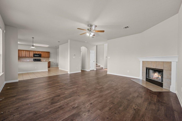 215 Gainer Dr, Hutto, TX 78634 - unfurnished living room with a ceiling fan, a tile fireplace, wood finished floors, and baseboards