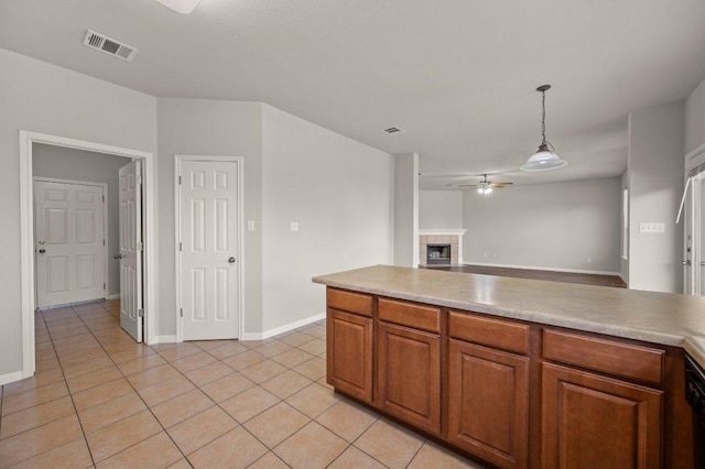 215 Gainer Dr, Hutto, TX 78634 - kitchen featuring light tile patterned flooring, ceiling fan, brown cabinets, pendant lighting, and light countertops