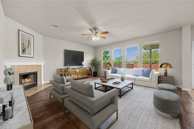 215 Gainer Dr, Hutto, TX 78634 - living room featuring wood finished floors, a ceiling fan, and a fireplace
