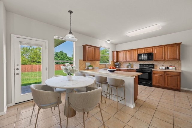215 Gainer Dr, Hutto, TX 78634 - kitchen with black appliances, tasteful backsplash, a peninsula, and light countertops