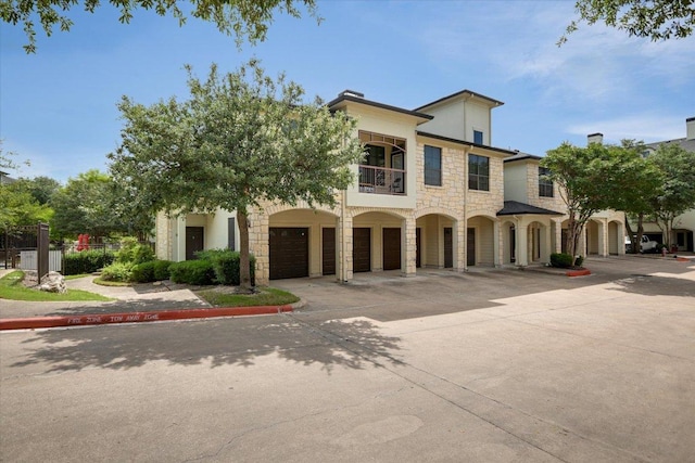 7701 Rialto Blvd Unit 1232, Austin, TX 78735 - view of front of house with stone siding, driveway, a balcony, a garage, and stucco siding