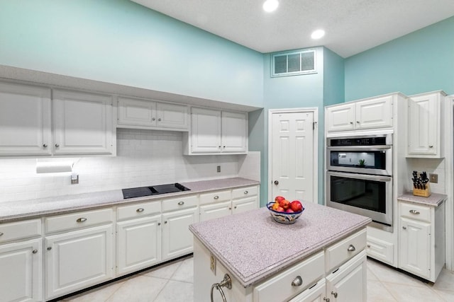10408 Cassia Dr, Austin, TX 78759 - kitchen featuring double oven, black electric stovetop, backsplash, light tile patterned floors, and white cabinets