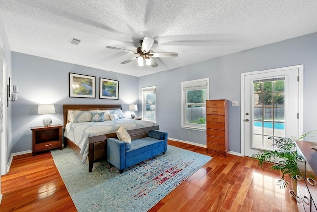 10408 Cassia Dr, Austin, TX 78759 - bedroom featuring access to outside, baseboards, wood finished floors, a ceiling fan, and a textured ceiling