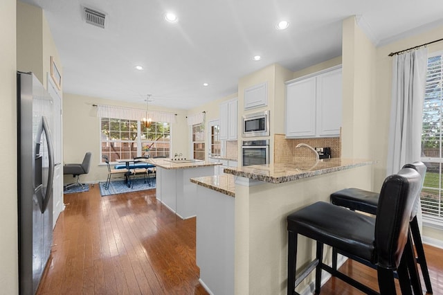 5302 Austral Loop, Austin, TX 78739 - kitchen featuring appliances with stainless steel finishes, a kitchen island, a peninsula, dark wood-style floors, and plenty of natural light