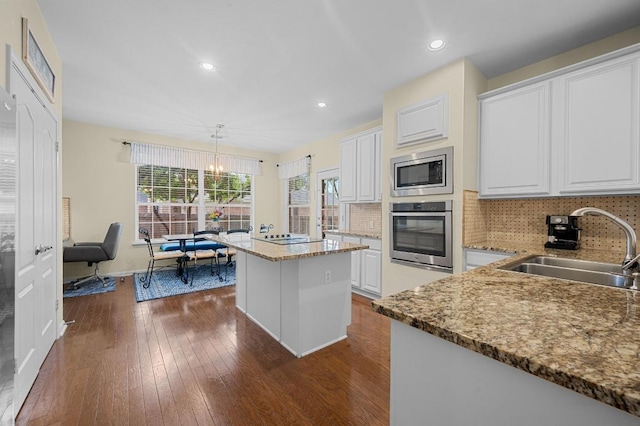 5302 Austral Loop, Austin, TX 78739 - kitchen with stainless steel appliances, a kitchen island, dark wood-type flooring, white cabinets, and tasteful backsplash