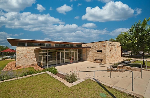 5302 Austral Loop, Austin, TX 78739 - back of property featuring a patio, stone siding, a sunroom, and a lawn
