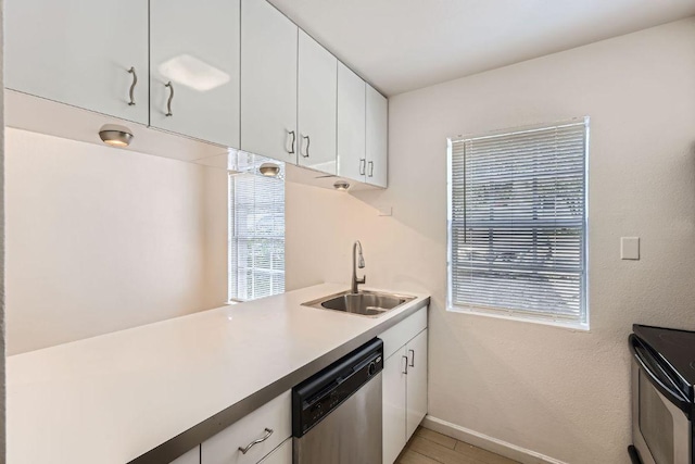 300 Crockett St Unit 115, Austin, TX 78704 - kitchen featuring stainless steel appliances, a sink, white cabinetry, light countertops, and baseboards