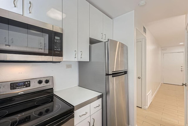 300 Crockett St Unit 115, Austin, TX 78704 - kitchen featuring appliances with stainless steel finishes, white cabinetry, light countertops, and baseboards