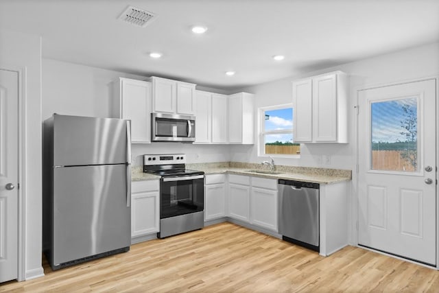 524 Aplite Pass, Maxwell, TX 78656 - kitchen with appliances with stainless steel finishes, white cabinetry, light wood finished floors, light stone counters, and recessed lighting