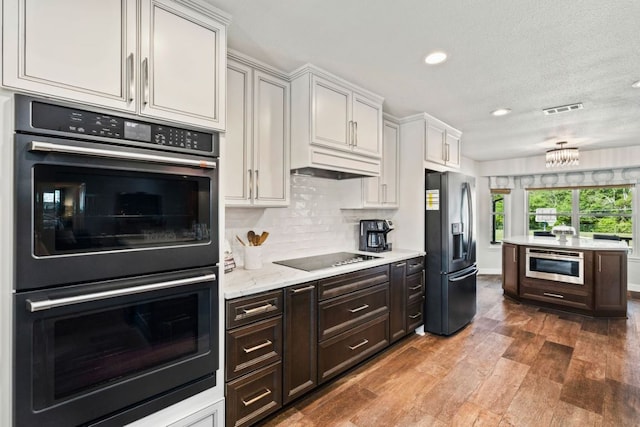 3701 Arrowhead Cir, Round Rock, TX 78681 - kitchen with black appliances, recessed lighting, wood finished floors, backsplash, and dark brown cabinets