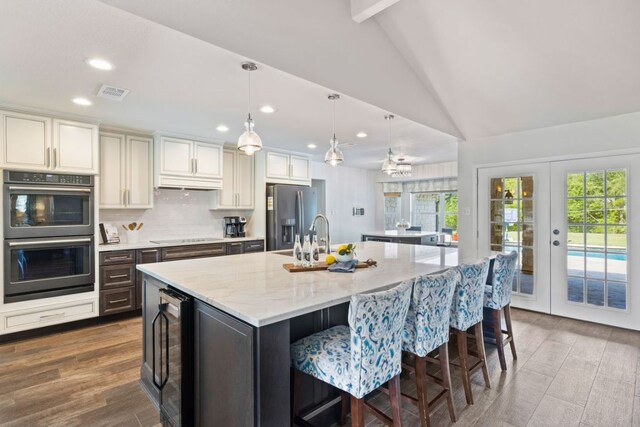 3701 Arrowhead Cir, Round Rock, TX 78681 - kitchen featuring black appliances, beverage cooler, lofted ceiling, a spacious island, and recessed lighting