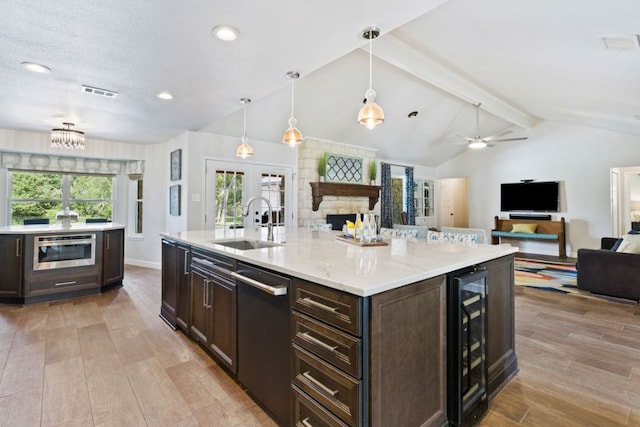 3701 Arrowhead Cir, Round Rock, TX 78681 - kitchen featuring stainless steel dishwasher, beverage cooler, open floor plan, dark brown cabinets, and light wood-style flooring