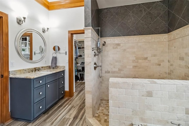 402 Lander Ln, Dripping Springs, TX 78620 - bathroom with walk in shower, vanity, a spacious closet, ornamental molding, and wood finished floors