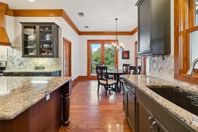 402 Lander Ln, Dripping Springs, TX 78620 - kitchen with a sink, dark wood-style flooring, a chandelier, glass insert cabinets, and hanging light fixtures