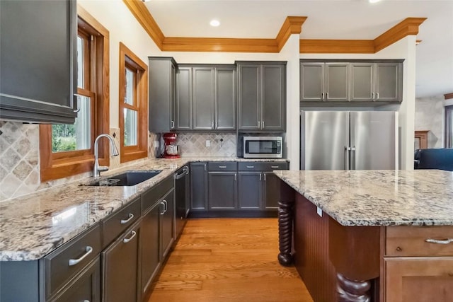 402 Lander Ln, Dripping Springs, TX 78620 - kitchen with appliances with stainless steel finishes, a sink, ornamental molding, light wood-style flooring, and light stone countertops