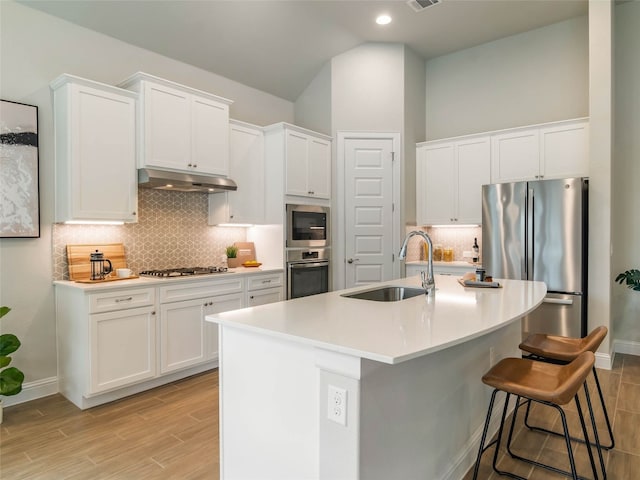 8505 Moccasin Path, Austin, TX 78736 - kitchen with appliances with stainless steel finishes, a sink, under cabinet range hood, light wood finished floors, and white cabinetry