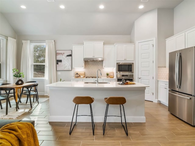 8505 Moccasin Path, Austin, TX 78736 - kitchen with appliances with stainless steel finishes, lofted ceiling, a sink, under cabinet range hood, and an island with sink