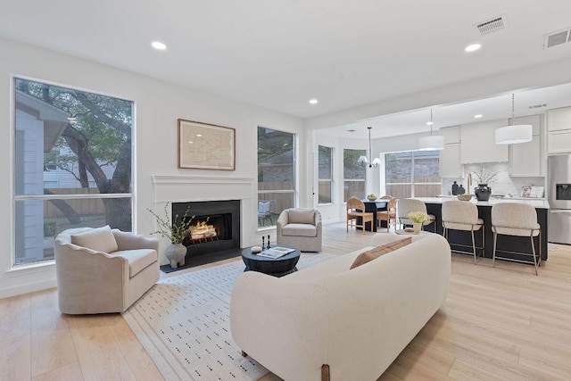5209 Concho Creek Bnd, Austin, TX 78735 - living room featuring light wood-style floors, a fireplace with flush hearth, recessed lighting, and a chandelier