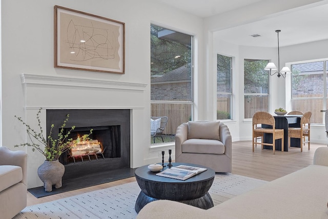 5209 Concho Creek Bnd, Austin, TX 78735 - living room featuring wood finished floors, a chandelier, and a fireplace with flush hearth