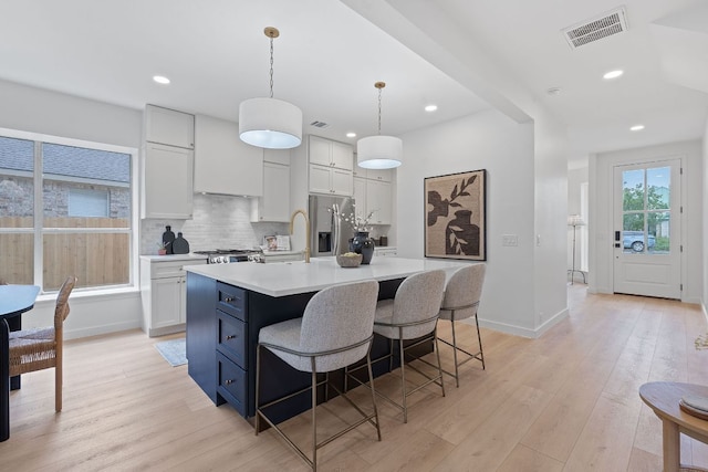 5209 Concho Creek Bnd, Austin, TX 78735 - kitchen featuring stainless steel refrigerator with ice dispenser, light wood-type flooring, light countertops, a center island with sink, and recessed lighting