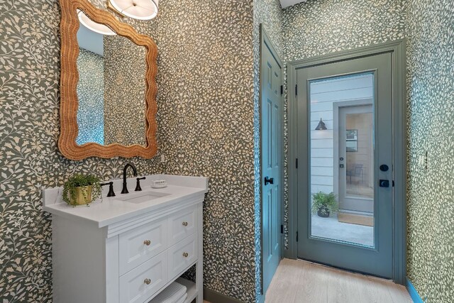 5209 Concho Creek Bnd, Austin, TX 78735 - bathroom with wallpapered walls, wood finished floors, and vanity