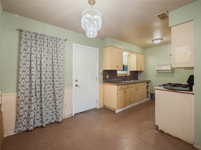 1021 Gardner Rd, Austin, TX 78721 - kitchen featuring a sink, dark countertops, a wainscoted wall, a chandelier, and hanging light fixtures