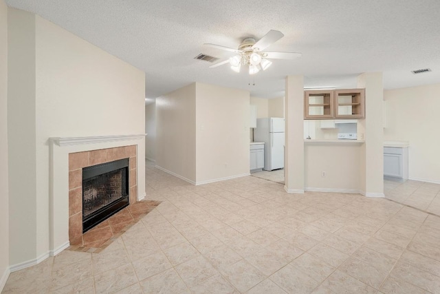 2202 Clayton Way, Cedar Park, TX 78613 - unfurnished living room featuring ceiling fan, a textured ceiling, a tiled fireplace, and baseboards