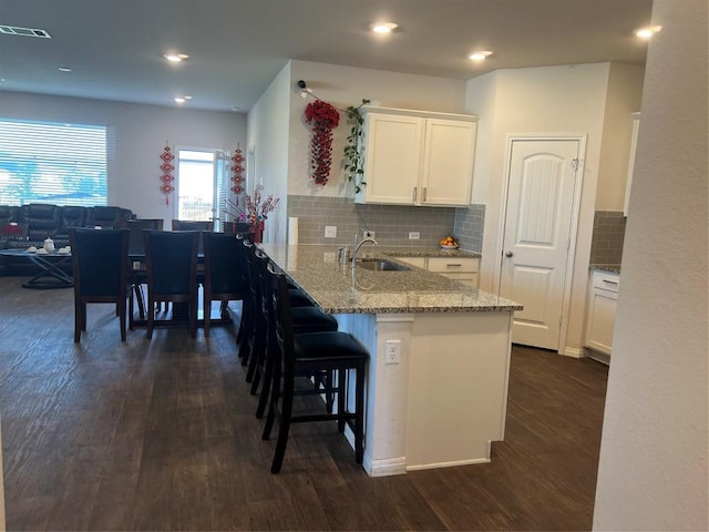 201 Abby Rd, Georgetown, TX 78626 - kitchen featuring dark wood-type flooring, white cabinets, a kitchen breakfast bar, a peninsula, and light stone countertops