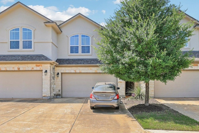 13400 Briarwick Dr Unit 1202, Austin, TX 78729 - view of property with stone siding, stucco siding, concrete driveway, an attached garage, and roof with shingles