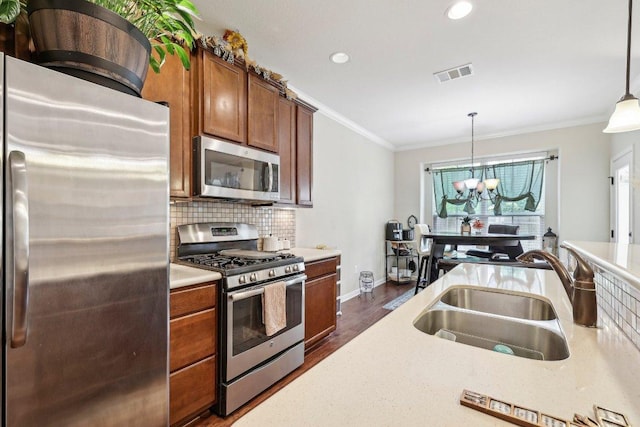 13400 Briarwick Dr Unit 1202, Austin, TX 78729 - kitchen with stainless steel appliances, crown molding, a sink, brown cabinets, and a chandelier