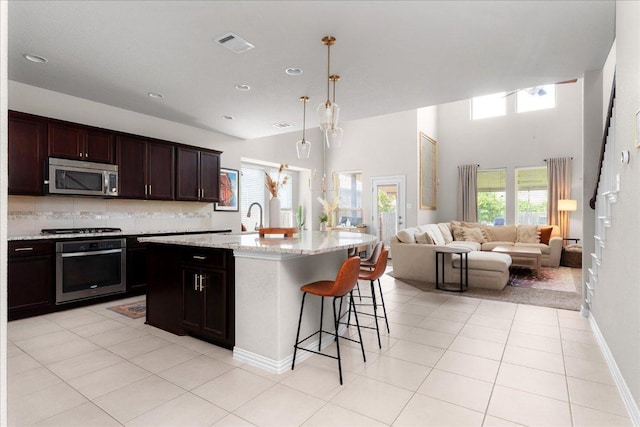 211 Joseph Dr, Buda, TX 78610 - kitchen with stainless steel appliances, open floor plan, healthy amount of natural light, a kitchen bar, and a high ceiling