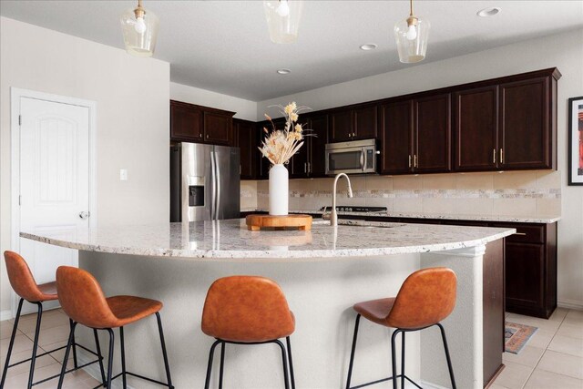 211 Joseph Dr, Buda, TX 78610 - kitchen featuring stainless steel appliances, light tile patterned flooring, tasteful backsplash, dark brown cabinets, and hanging light fixtures