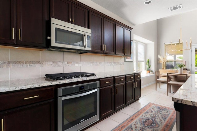 211 Joseph Dr, Buda, TX 78610 - kitchen featuring appliances with stainless steel finishes, tasteful backsplash, light stone countertops, light tile patterned flooring, and dark brown cabinets
