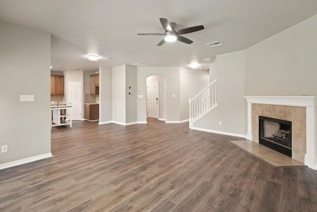 1121 Boxwood Loop, Georgetown, TX 78628 - unfurnished living room with arched walkways, a ceiling fan, dark wood-type flooring, baseboards, and a fireplace