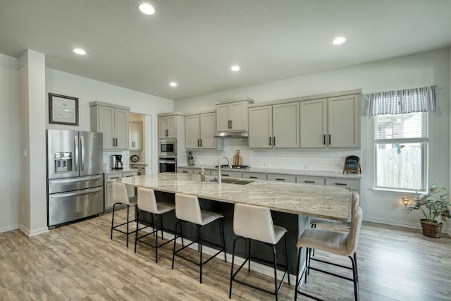 19500 Chayton Cir, Pflugerville, TX 78660 - kitchen with appliances with stainless steel finishes, baseboards, a breakfast bar area, tasteful backsplash, and light wood finished floors