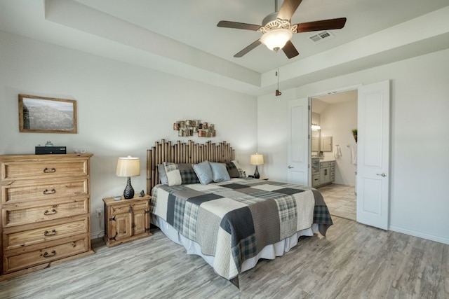 19500 Chayton Cir, Pflugerville, TX 78660 - bedroom featuring light wood-style floors, a raised ceiling, ensuite bathroom, ceiling fan, and baseboards
