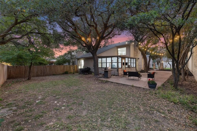 8115 Raintree Pl, Austin, TX 78759 - back of property at dusk featuring a fenced backyard, a patio area, and a sunroom