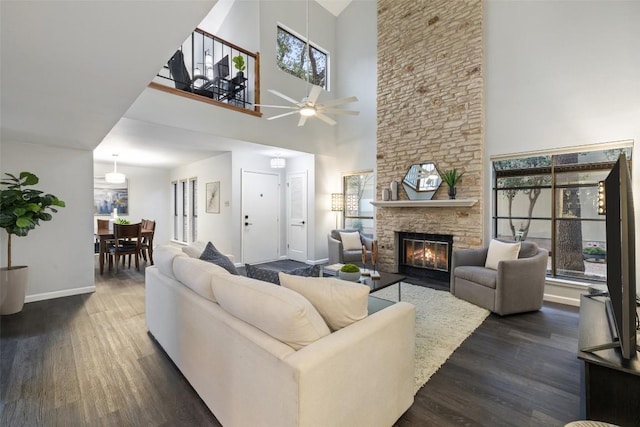 8115 Raintree Pl, Austin, TX 78759 - living room with dark wood finished floors, a towering ceiling, baseboards, a fireplace, and a ceiling fan