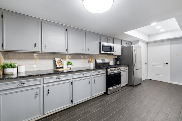 8115 Raintree Pl, Austin, TX 78759 - kitchen featuring appliances with stainless steel finishes, dark wood finished floors, tasteful backsplash, and dark stone counters