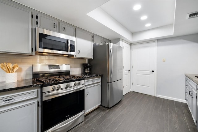 8115 Raintree Pl, Austin, TX 78759 - kitchen with stainless steel appliances, dark wood-type flooring, gray cabinetry, backsplash, and dark stone countertops