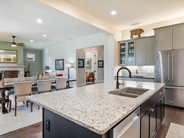 121 Wild Honeysuckle Way, San Marcos, TX 78666 - kitchen with stainless steel appliances, a kitchen island with sink, light stone counters, dark wood-style flooring, and recessed lighting