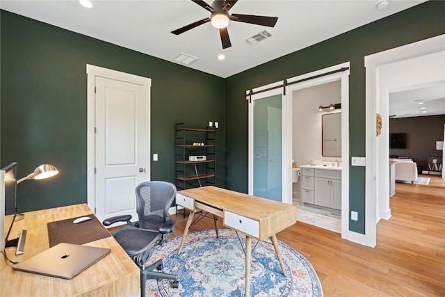 22005 Briarcliff Dr, Spicewood, TX 78669 - home office with ceiling fan, light wood finished floors, recessed lighting, a sink, and a barn door