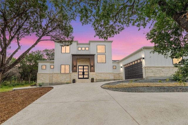 22005 Briarcliff Dr, Spicewood, TX 78669 - contemporary house featuring stone siding, concrete driveway, an attached garage, and board and batten siding