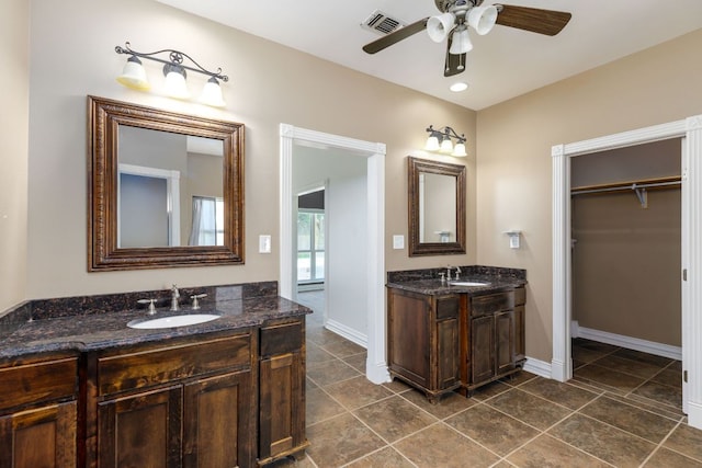 12011 Fm 1150th Rd, Luling, TX 78648 - bathroom featuring ceiling fan, two vanities, baseboards, a spacious closet, and tile patterned floors