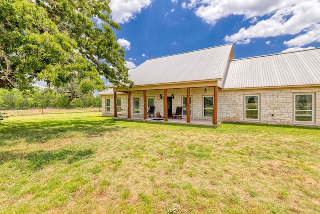 12011 Fm 1150th Rd, Luling, TX 78648 - rear view of house featuring stone siding, a patio, a lawn, and metal roof